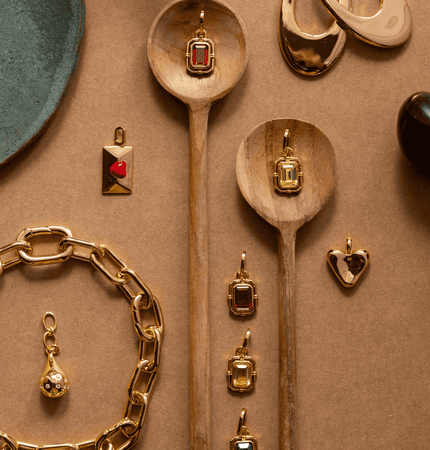 Gold jewelry with gemstones on a beige surface