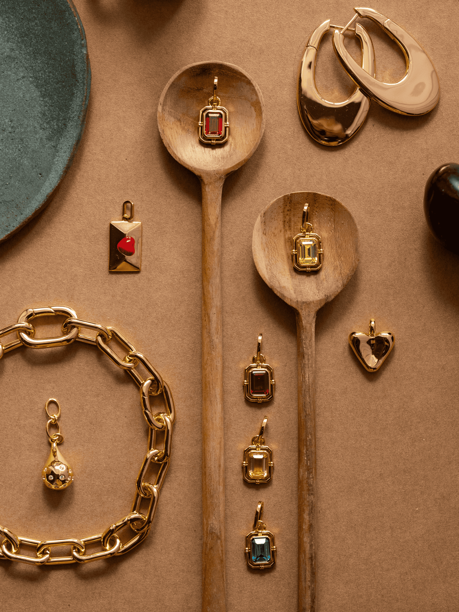 Gold jewelry with gemstones on a beige surface